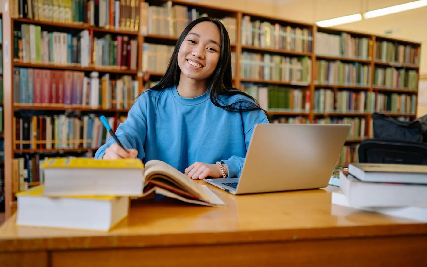 Studentin mit Laptop in einer Bibliothek